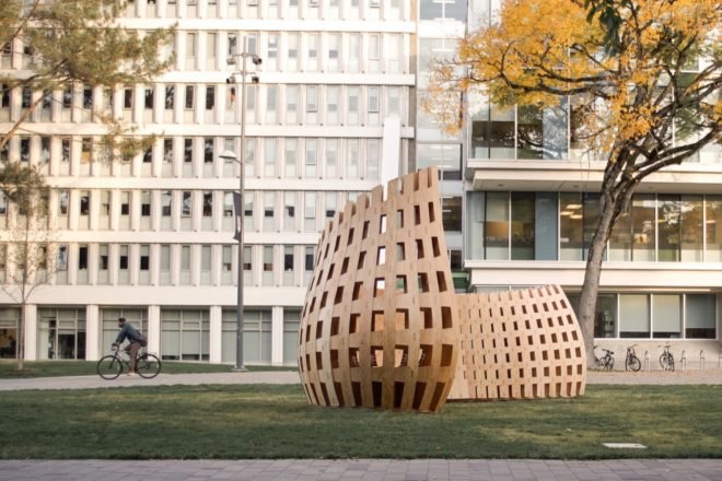 curved wood pavilion in front of a college building