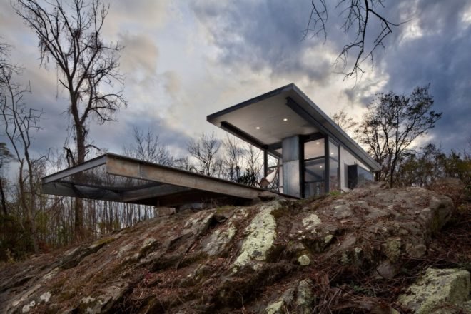 two flat roofs of a cabin jutting out over a rocky ledge