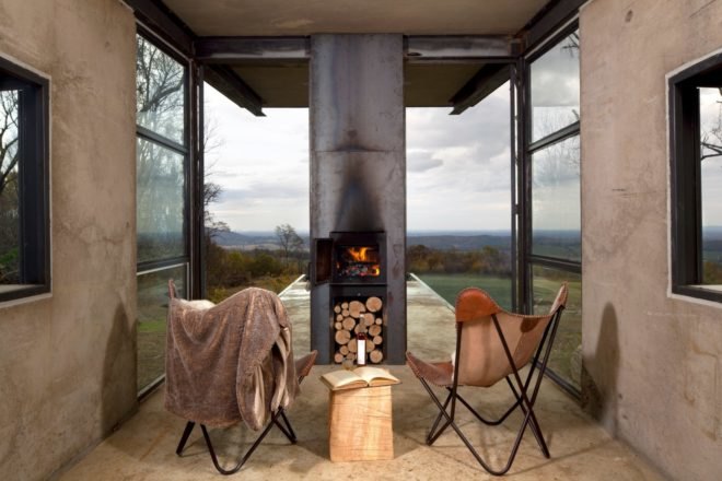 two chairs facing a fireplace with glass facade in the background