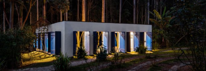 rectangular white building with blue shutters lit up at night