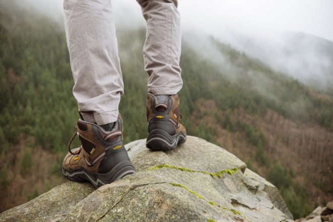 close-up of person wearing boots standing on a rock