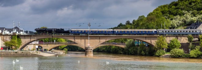 blue train on a bridge above a river
