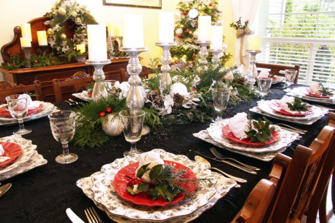 dinner table with centerpiece of candles and evergreen branches