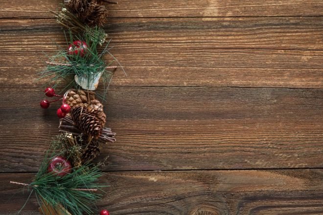 evergreen garland, pinecones and apples on wood table