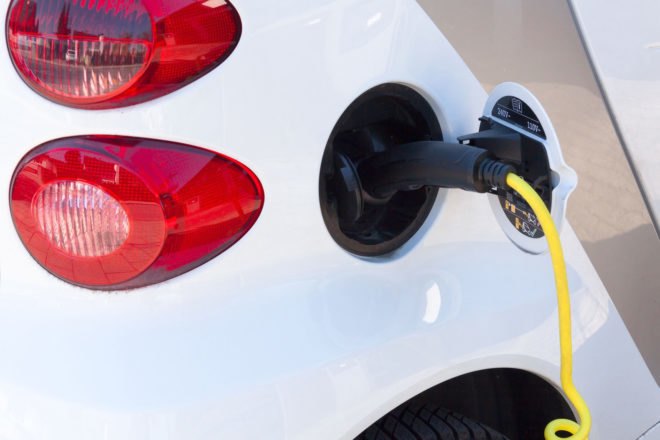 close-up of white electric car plugged in to a charger