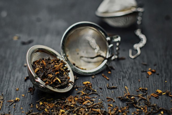 opened metal tea strainer spilling out loose leaf tea