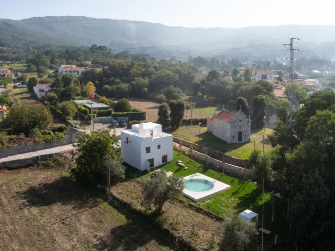 white home with pool surrounded by greenery