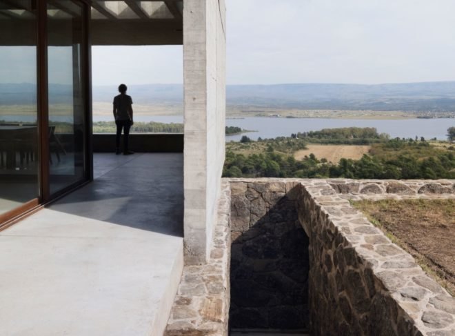 exterior of concrete home with person standing on a patio