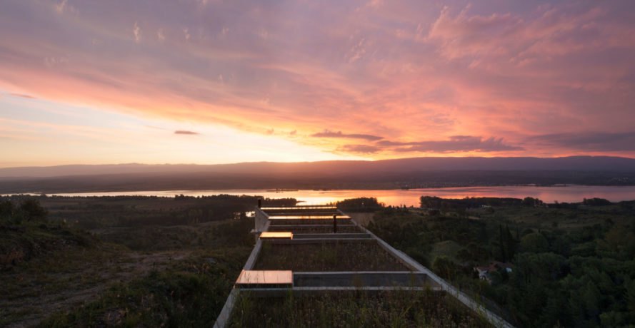 a rectangular home with green roof at sunset