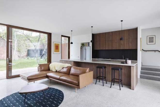 kitchen and living area of the home with brown furniture and wood cabinets
