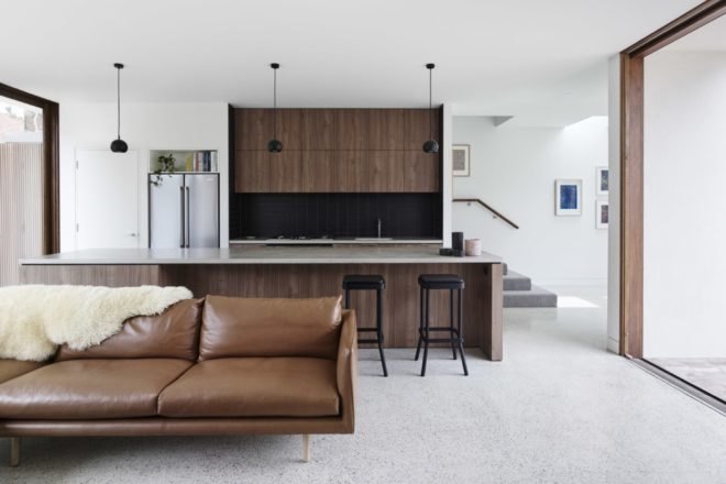 brown couch is positioned in front of kitchen area
