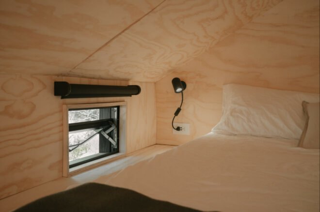 bed next to window with pitched ceiling
