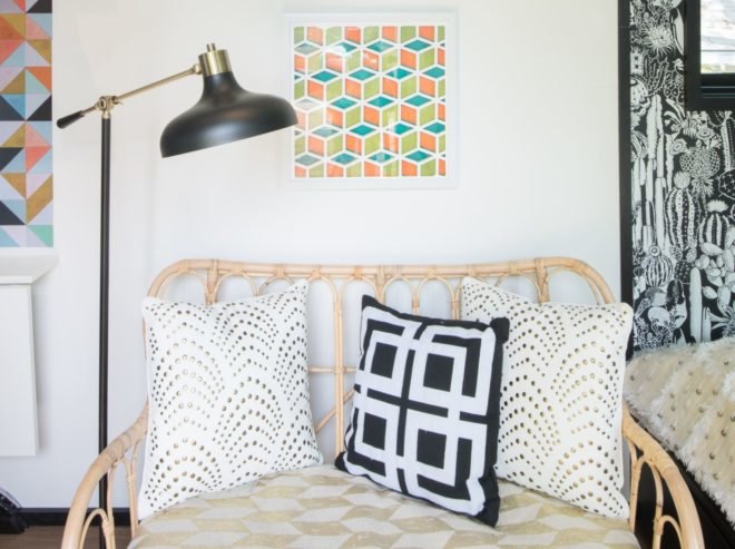 a wicker loveseat with patterned pillows