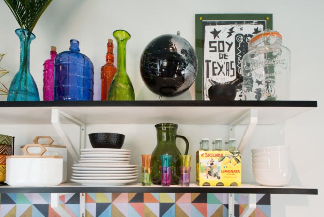 two shelves with plates and bottles and additional kitchen knickknacks