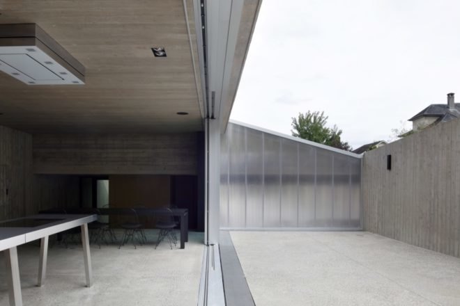 gray room with long black dining table near glass wall opened to an outdoor patio