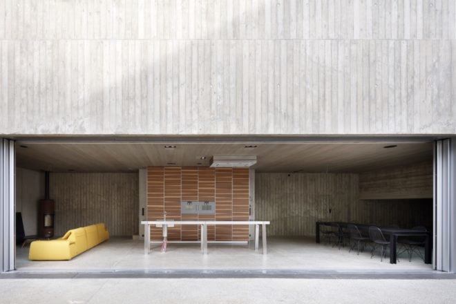 gray room with yellow couch and black dining table open to an outdoor patio