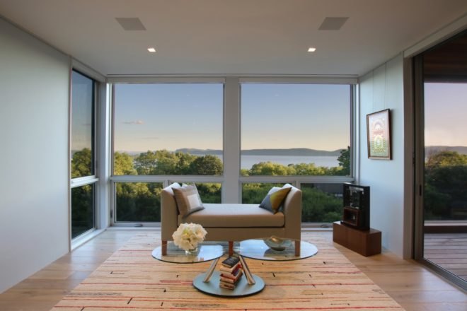 small tan seat in front of glass walls with views of Hudson River