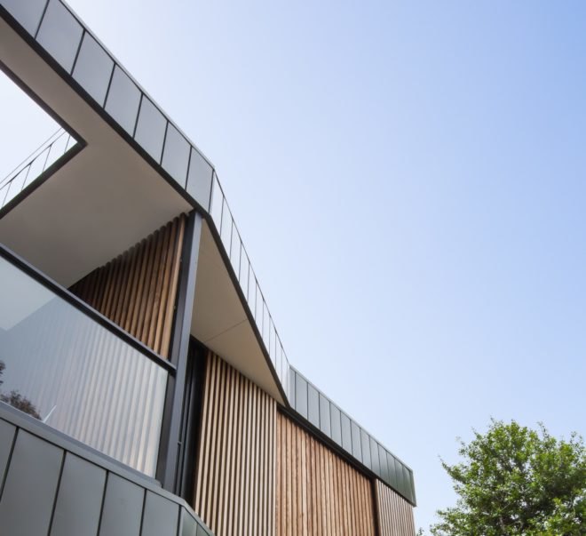 side of timber and black home against blue sky