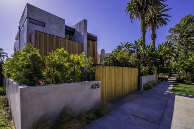 street view of the home with plants adorning the gate entrance