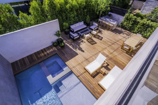 aerial view of the home's backyard with pool, bbq and lounge chairs and couches around fire pit