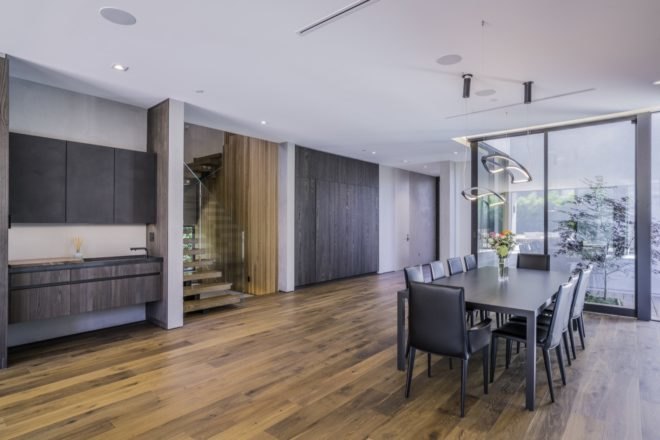 large windows illuminate dining area and black dining table with a view towards the staircase