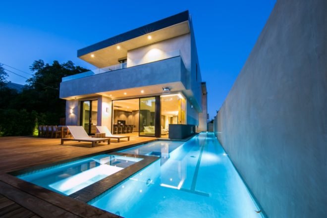 pool view of the home with lights illuminating the pool and home at night