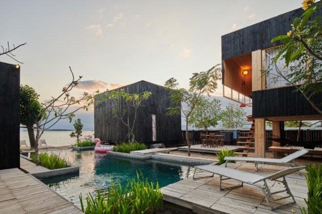 charred timber huts in front of a pool