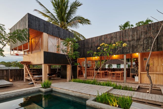 charred timber huts in front of a pool