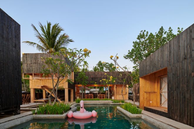 charred timber huts in front of a pool