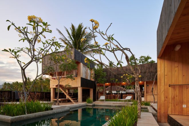 wooden cabins on stilts behind a pool