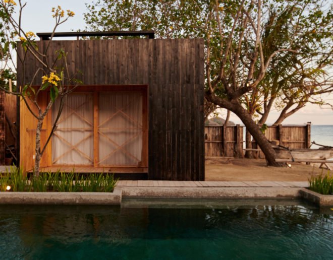 charred timber huts in front of a pool