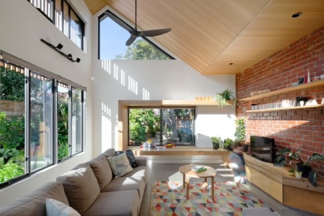 living area with exposed brick wall, large glass windows and tan sofa