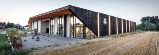 black timber building with light panels on the facade