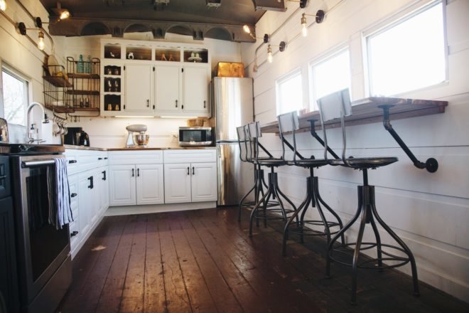 kitchen with white cabinets, dark wood floors, and fold out dining table from the wall