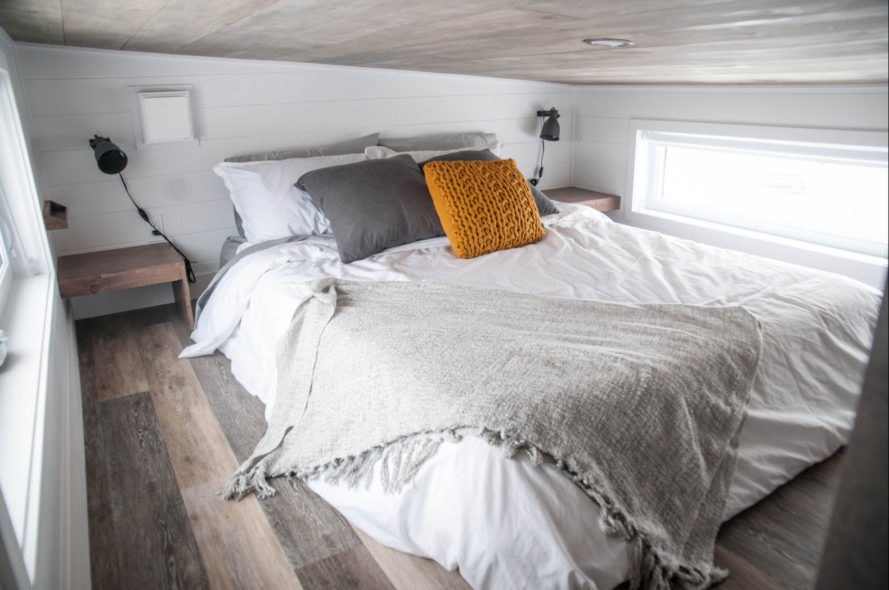 queen sized bed with orange and grey pillows