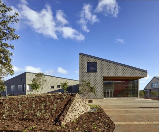 gray textured building with native plants in front