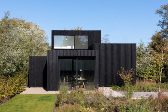 all black home with walkway surrounded by greenery