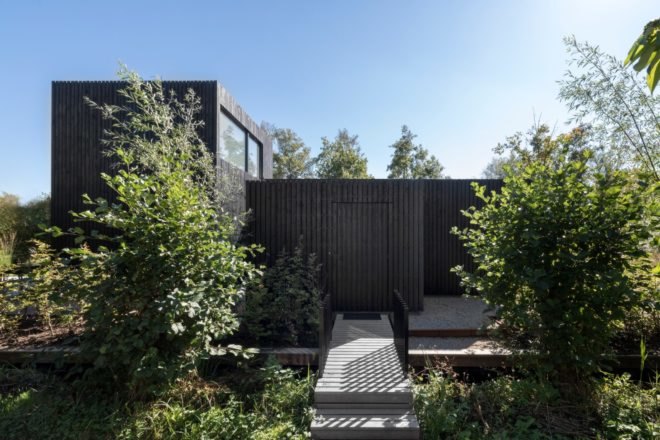 all black home with walkway surrounded by greenery