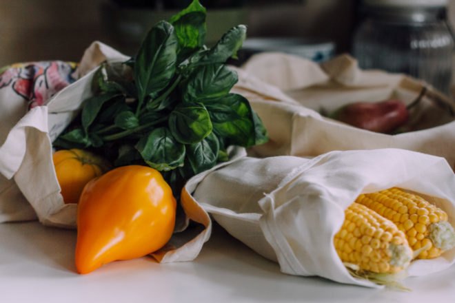 cloth reusable grocery shopping bag filled with various vegetables