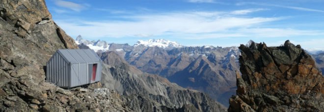 tiny gray shelter on mountain ridge