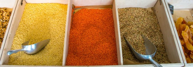 colorful dried goods in separate wood containers with metal scoops