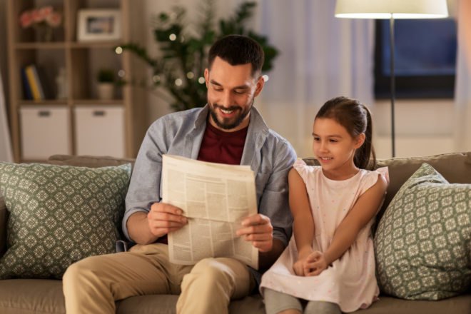father reading newspaper to child