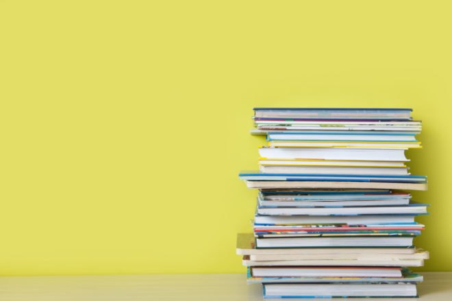 stack of children's books in front of yellow wall