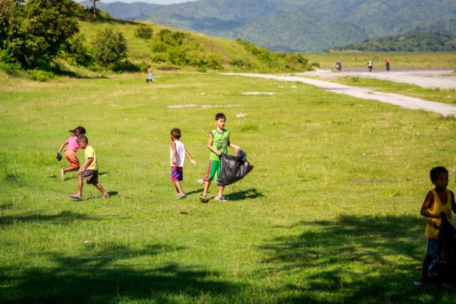 children picking up trash on green grass