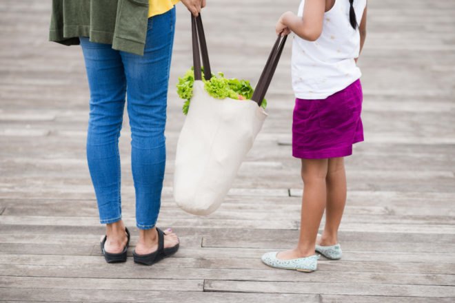 mother and daughter carrying a reusable grocery bag