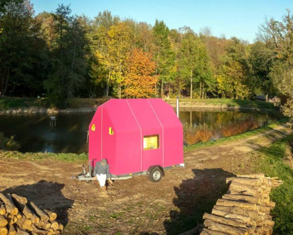 bright pink tiny home surrounded by trees in autumn