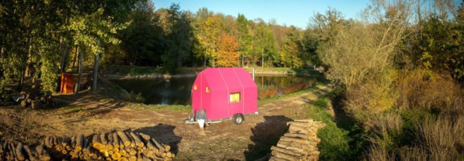 bright pink tiny home surrounded by trees in autumn