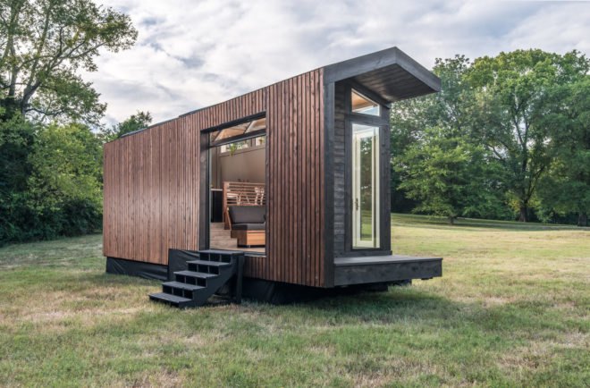 black and dark wood tiny home with large glass door open to outside