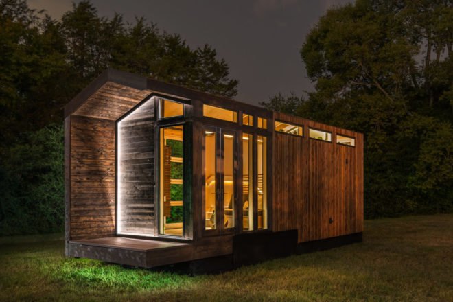 wood tiny home lit up at night