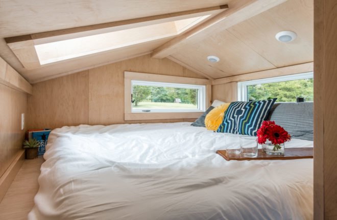 white bed in light wood-lined loft space